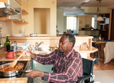 Wheelchair user cooking a meal at home in a sunny apartment
