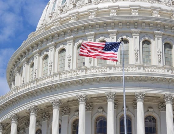 U.S. Capitol Building with U.S. flag waving in front, on a sunny day