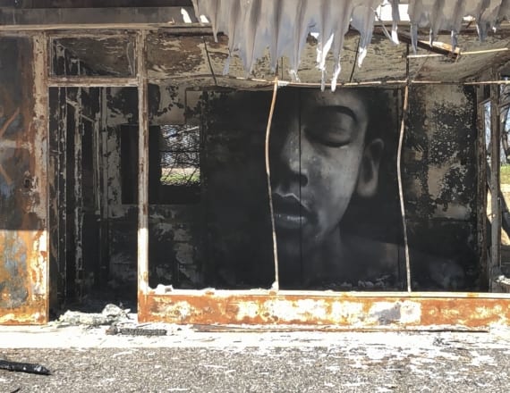 Mural painted on the wall of a burned out building in Butte County, CA after the Paradise fire. The mural shows the face of a young person with closed eyes.