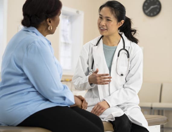 A young doctor having a friendly conversation with a middle aged patient in street clothes at a clinic