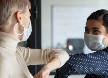 Two coworkers give each other a friendly elbow bump