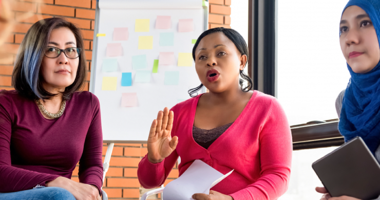 Three women of color participating in a listening session; one of them is speaking forcefully to the presenter, who is not shown.